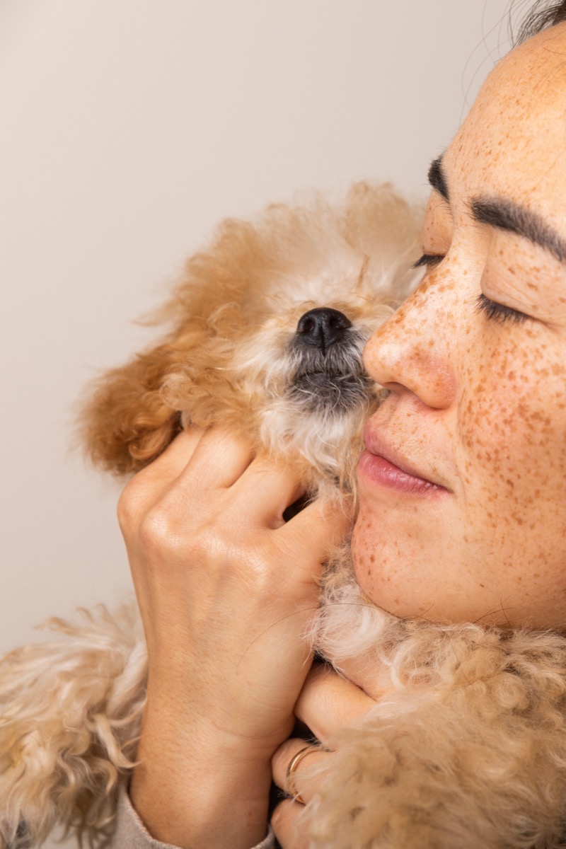 A pet owner cuddling a golden puppy